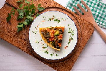 Piece of roasted vegetarian vegetable quiche. Top view table with decorations.