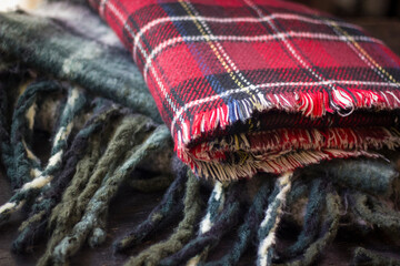 Stack of folded knitted wool scarf, Season of warm knitwear red, green, wood.