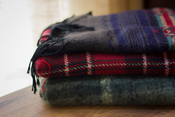 Stack of folded knitted wool scarf, Season of warm knitwear red, green, wood.