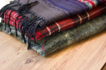Stack of folded knitted wool scarf, Season of warm knitwear red, green, wood.