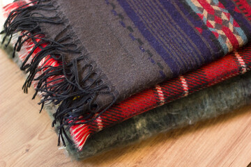 Stack of folded knitted wool scarf, Season of warm knitwear red, green, wood.