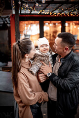 a young family with a small child in autumn in a cafe in brown and orange tones on an outdoor terrace hug and kiss, a happy family walks outside in autumn