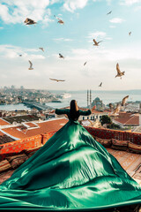 Girl in a green dress with a long train on the terrace view of the Bosphorus in Istanbul