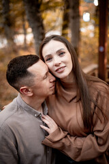 a young couple guy with a girl in autumn in a cafe in brown and orange tones on an outdoor terrace hugging and kissing, love or Valentine's day