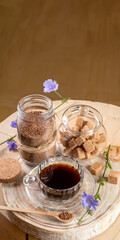Chicory tea cup, jars of granulated soluble chicory and cane sugar, on wooden stump. Copy space.