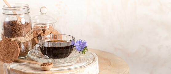 Cup of chicory drink, jars of granulated chicory, cane sugar on wooden stump on beige. Copy space.