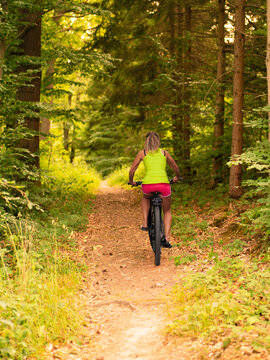 a woman rides her bicycle in the forest in summer