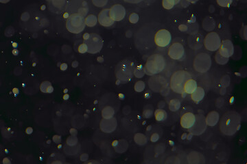 Defocused bokeh lights in various sizes and colors on a dark background creating a dreamy and...