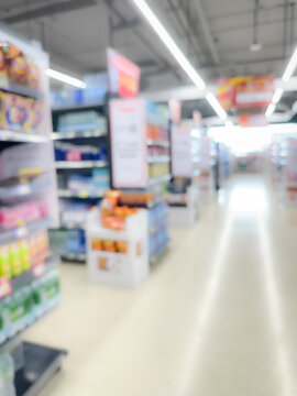 Blurred view of a brightly lit supermarket aisle with various product shelves on both sides. .