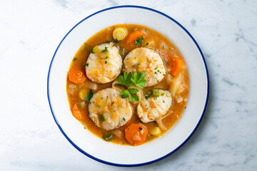 Stewed hake medallions with vegetables. Top view table with  decorations.