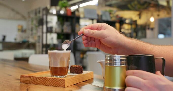 Professional barista preparing a caramel coffee with cinnamon on a wooden table in a specialized cafe