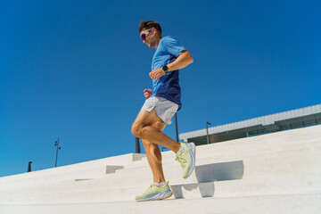 A Man Runs on Modern White Stairs Under a Clear Blue Sky During a Sunny Day