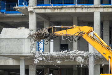 Excavator machine with hydraulic crashers at demolition of the house. House being demolished by special machinery.