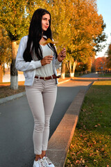 young beautiful girl walking on concrete parapet in autumn park in rays of sunlight