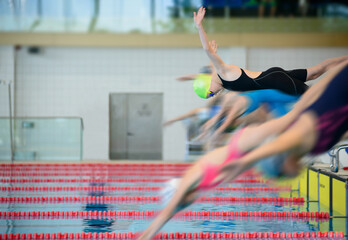Swimmer girls start from the starting table in the pool