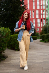 Young woman walks through urban park in morning, sipping coffee casually