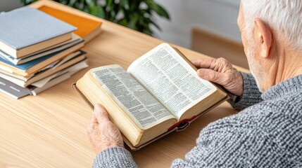 Naklejka premium An elderly man with white hair enjoys reading the Bible at a wooden table in his home. The atmosphere is warm and inviting, illuminated by soft natural light