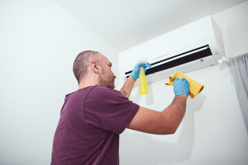 Man cleaning and maintaining air condition unit at home.