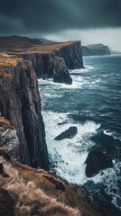 Naklejka premium A rugged cliffside meets turbulent ocean waves under a moody sky, creating a dramatic coastal landscape filled with natural beauty.