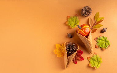 Autumn holidays concept. Autumn background with ice cream cones, pine cones, pumpkins, acorns and autumn leaves, on beige background, top view flat lay copy space
