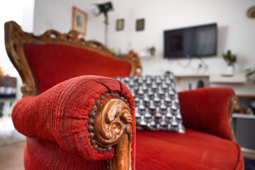 A cozy, vintage, red armchair with handcrafted wooden details. It stands in the room.