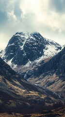 Obraz premium A stunning mountain landscape featuring a snow-covered peak under a dramatic sky, showcasing natural beauty and rugged terrain.
