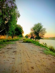 Sunset Over a Serene Village Path by the River