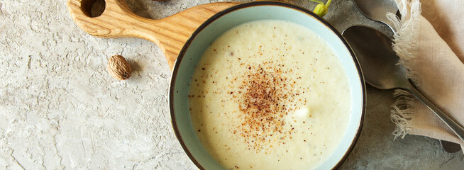 bowl of celery root soup with nutmeg on a table, top view
