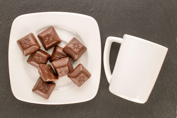 Dark chocolate with ceramic dishes on slate stone, macro, top view.