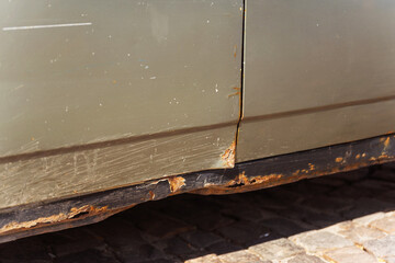 Closeup of a rusty car with a yellow light on its side