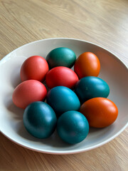 Bowl of vibrant colored Easter eggs standing on a wooden surface, beautifully festive and joyful atmosphere. Easter and religious holidays