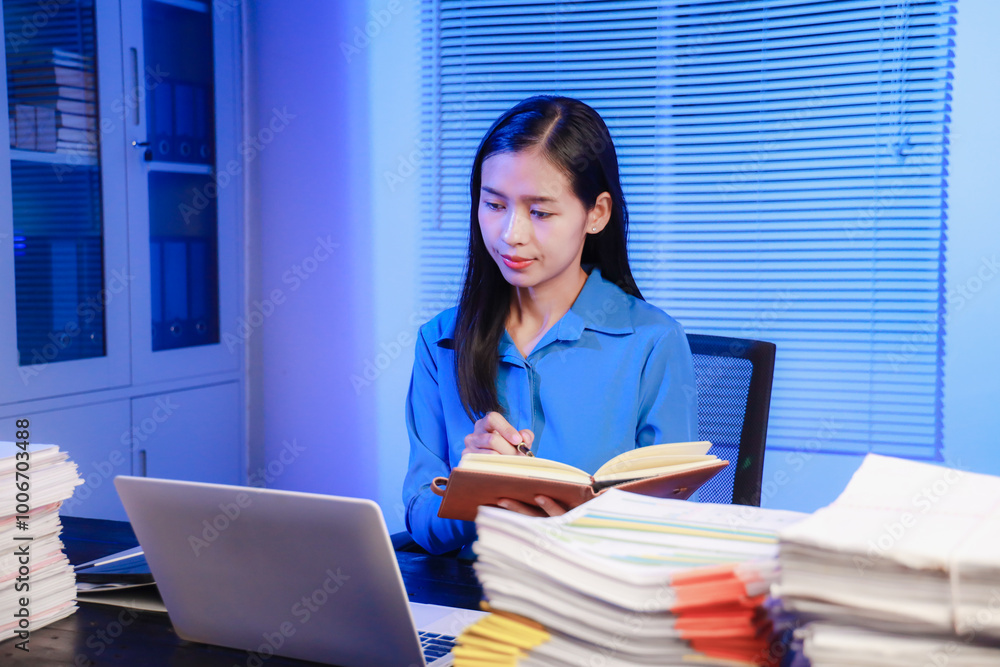 Wall mural asian businesswoman working hard in front of computer and many documents on desk at office late at n