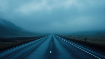 Fototapeta premium A long, empty highway stretches into the distance, shrouded in thick fog with a dramatic, moody atmosphere