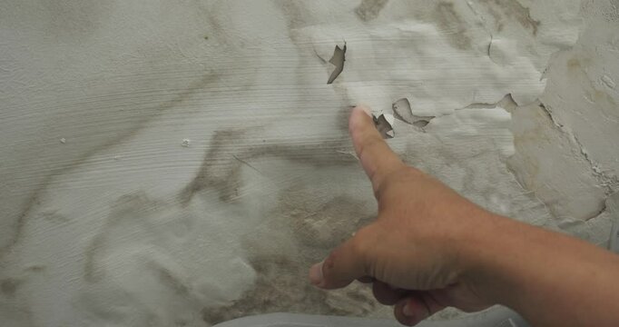 Male finger is peeling paint on ceiling, Office building or house problem for house service. High definition shot at 4K, 50 fps video footage.