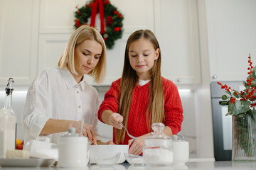 A mother teaches her daughter to make cookies.