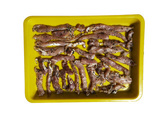 making sun-dried pork. It's drying in the sun.Food preservation by sun drying pork.Pieces of bacon with black sesame seeds on a yellow plate