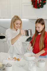 A mother teaches her daughter to make cookie dough. Mother and daughter cook together.