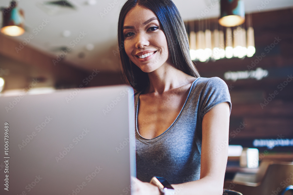 Poster portrait of happy female student resting in comfortable cafeteria with modern laptop computer for e 