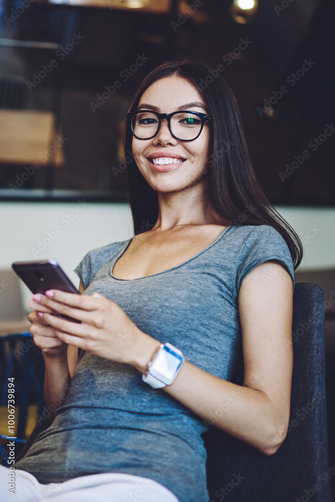 Poster portrait of cheerful hipster girl in new spectacles looking at camera while updating software setups