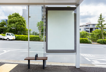 Vertical blank billboard at a bus stop shelter on a street in Tokyo, near by a park. Copy space...