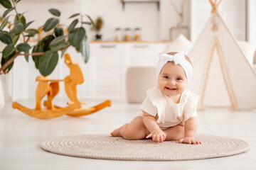 smiling baby girl playing sitting on the floor in white clothes