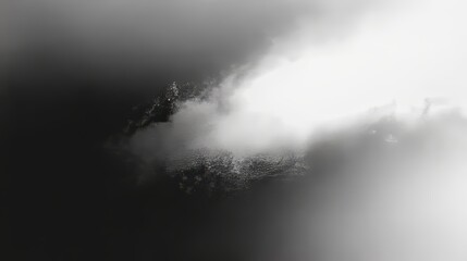 Fototapeta premium Ethereal clouds envelop a hidden mountain peak, creating a captivating monochromatic scene of nature's mysterious beauty.