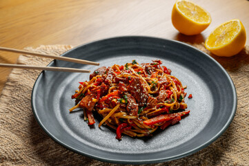 Delicious Asian udon dish with chicken and vegetables with soy sauce and sesame seeds sprinkled on...