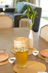 Dining table set with iced tea, bamboo steamer, and small dishes for family meal