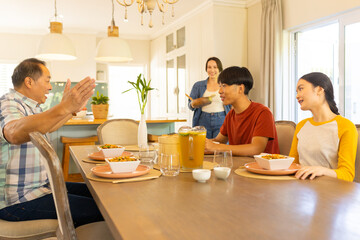 Multiracial family enjoying meal together, smiling and talking at dining table in kitchen