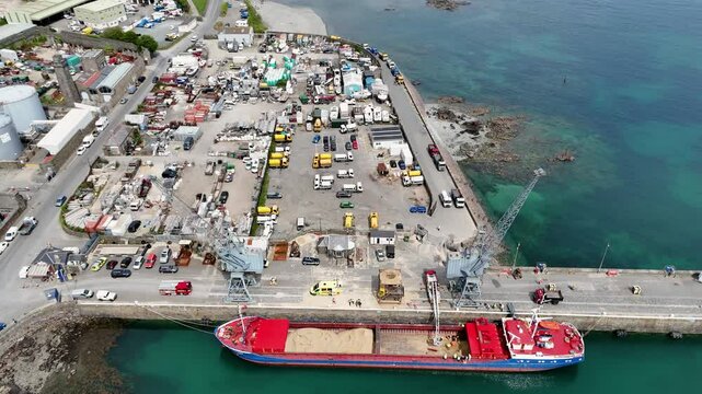Flight over ship being unloaded on docks ,public works depot and boat yard,St Sampson&rsquo;s Harbour Guernsey on bright sunny day