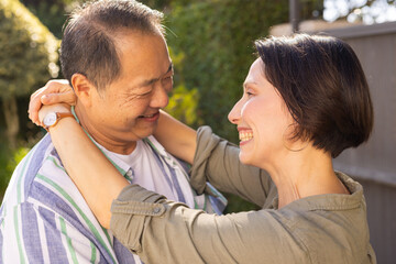 Smiling multiracial middle-aged couple embracing outdoors, enjoying quality time together in garden