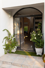 Naklejka premium Outdoors, Open front door of modern home with potted plants and inviting entryway