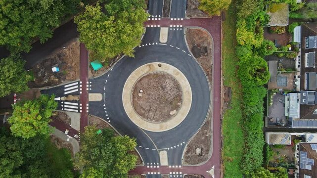 Top down aerial of roundabout with bicycle lanes under construction in a small Dutch town - drone ascending