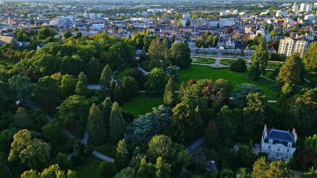 Sideways aerial movement around the Parc du Thabor's huge parkside, church in background, Rennes in France.